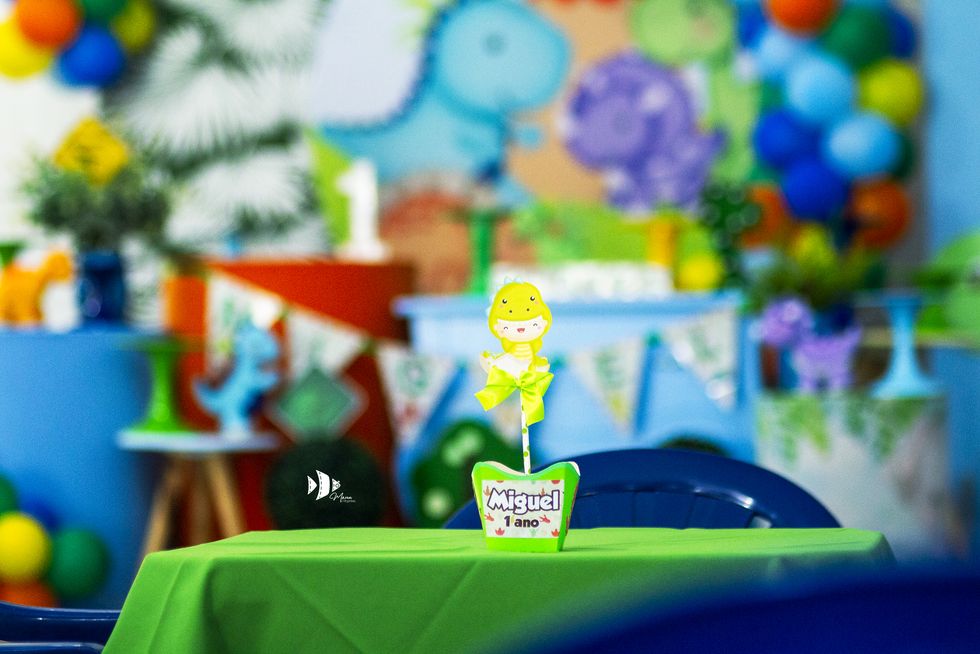 Detalhe temático de dinossauro com o nome do aniversariante na mesa decorada