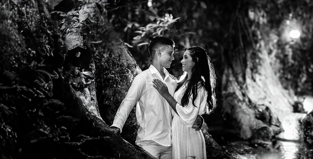 Retrato em preto e branco com luz de contorno: o acabamento visual destaca a presença do casal.