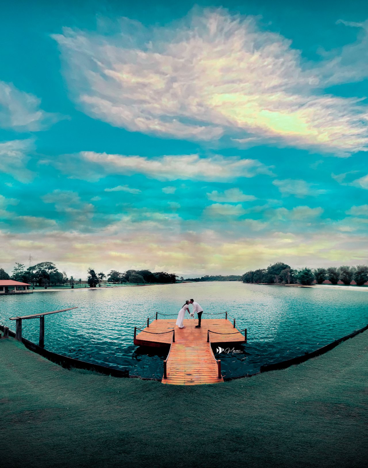 Roberta e Renato em um retrato panorâmico junto ao lago e à vegetação, em Rolim de Moura.